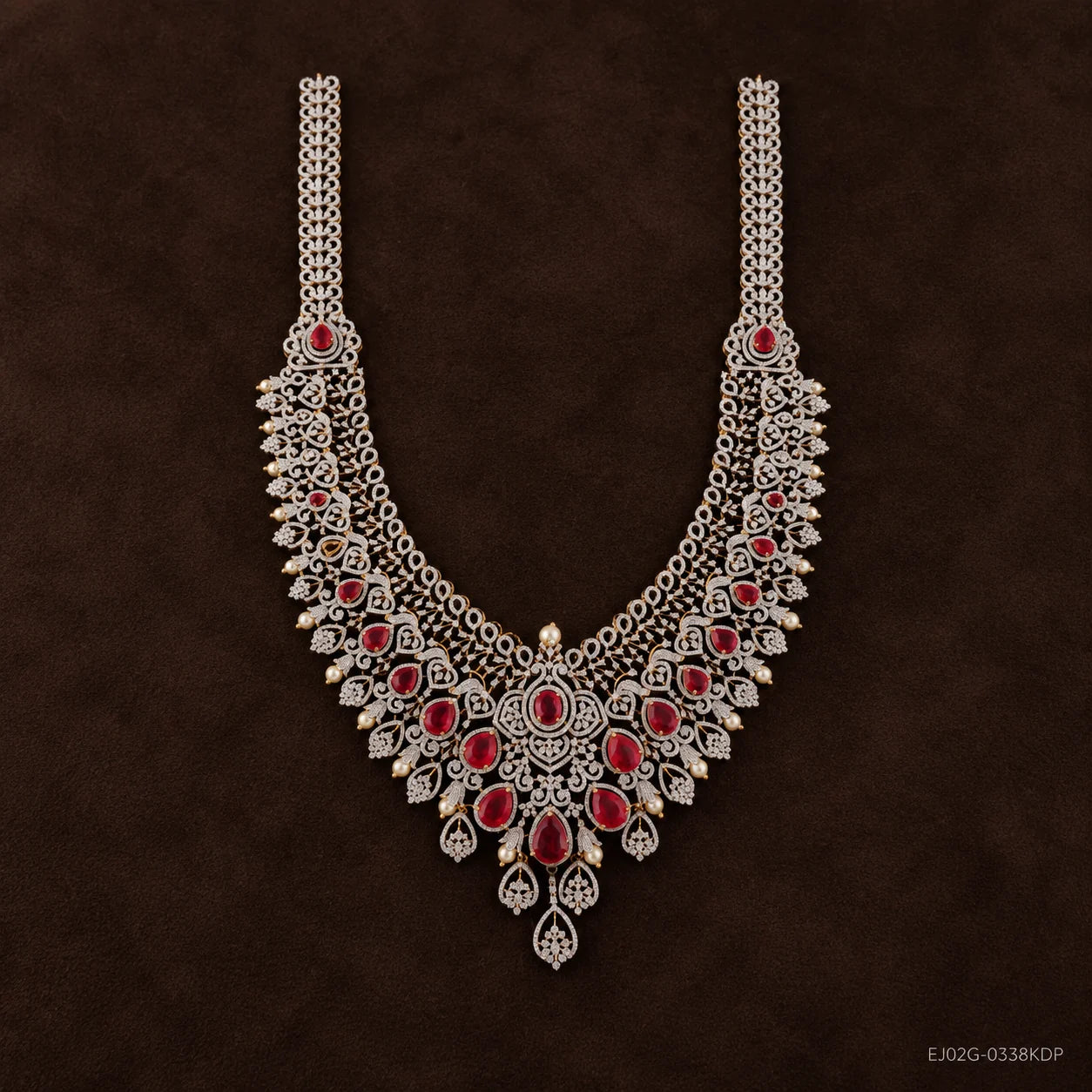 Straight-on view of long necklace on dark brown background, central floral pendant with red stones