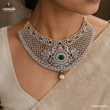 Detailed view of a choker necklace on the neck showing the peacock design, green stone drops and pearl pendant