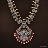 Close-up of the pendant showing peacock motifs, green stones and pink stone border with pearl drops