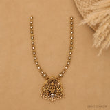 Full flat-lay view of the long necklace on beige fabric showing the beaded chain and pendant with drops