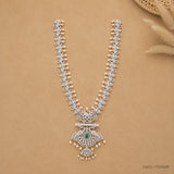 Long necklace laid flat in a V shape on beige fabric, showing full chain and pendant