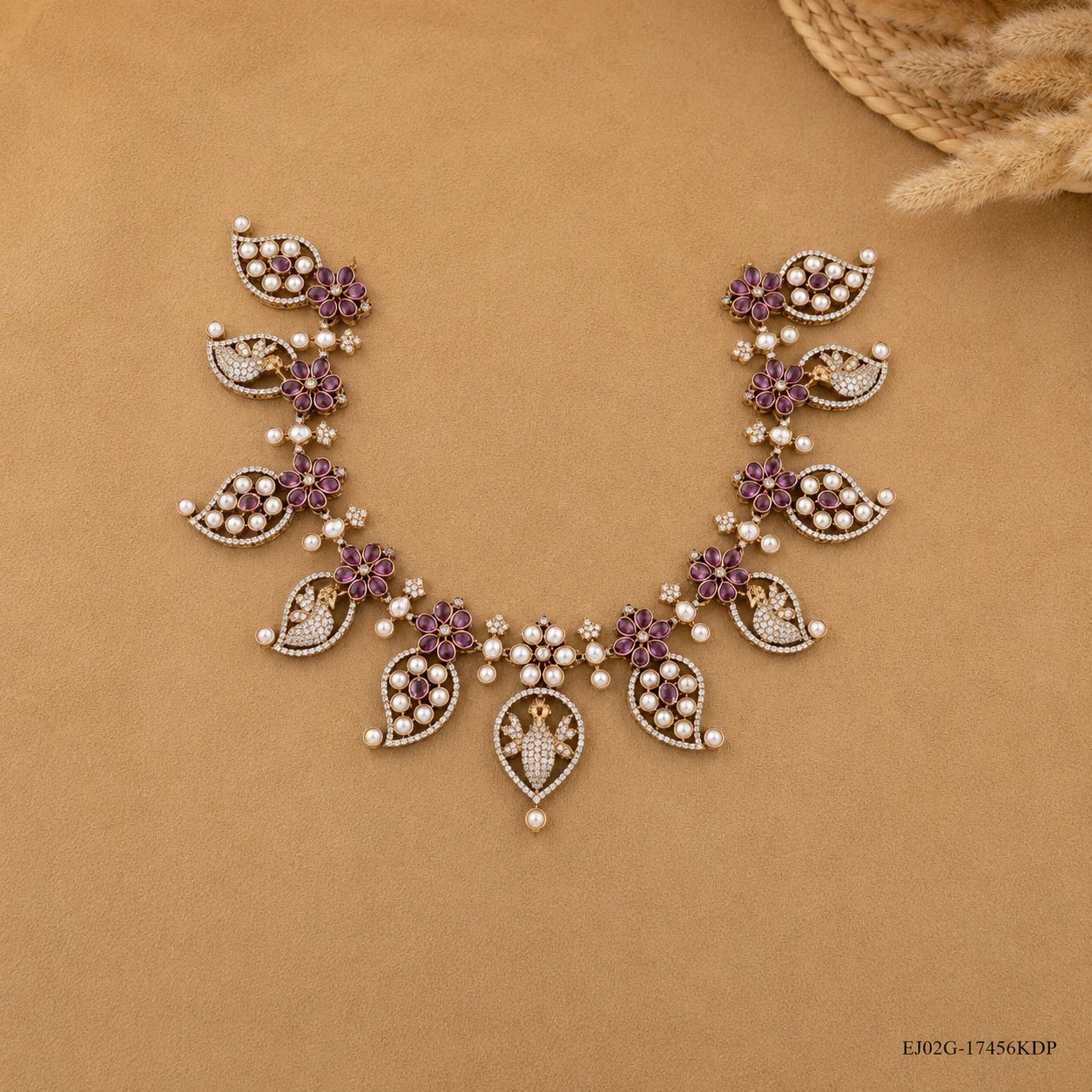 Overhead view of the Victorian pink necklace arranged on a beige backdrop with straw decor
