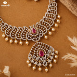 Flat lay of silver necklace and detachable pendant with pink stones and pearl drops on brown fabric background