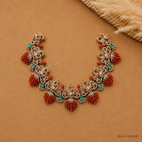 Flat lay of the Victorian necklace spread open on beige fabric highlighting scrollwork and coral bead drops