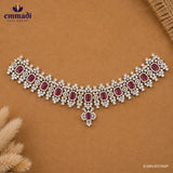 Flat lay of a pink and white CZ choker with pendant drop placed on a tan background beside dried flowers