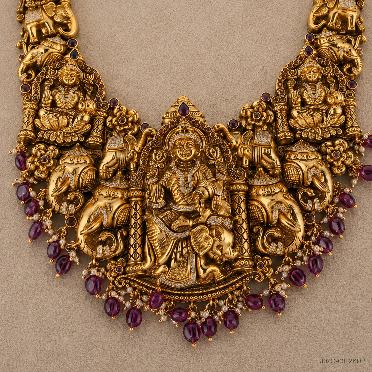 Close-up flat-lay of the central pendant with seated deity, elephants and pink bead drops
