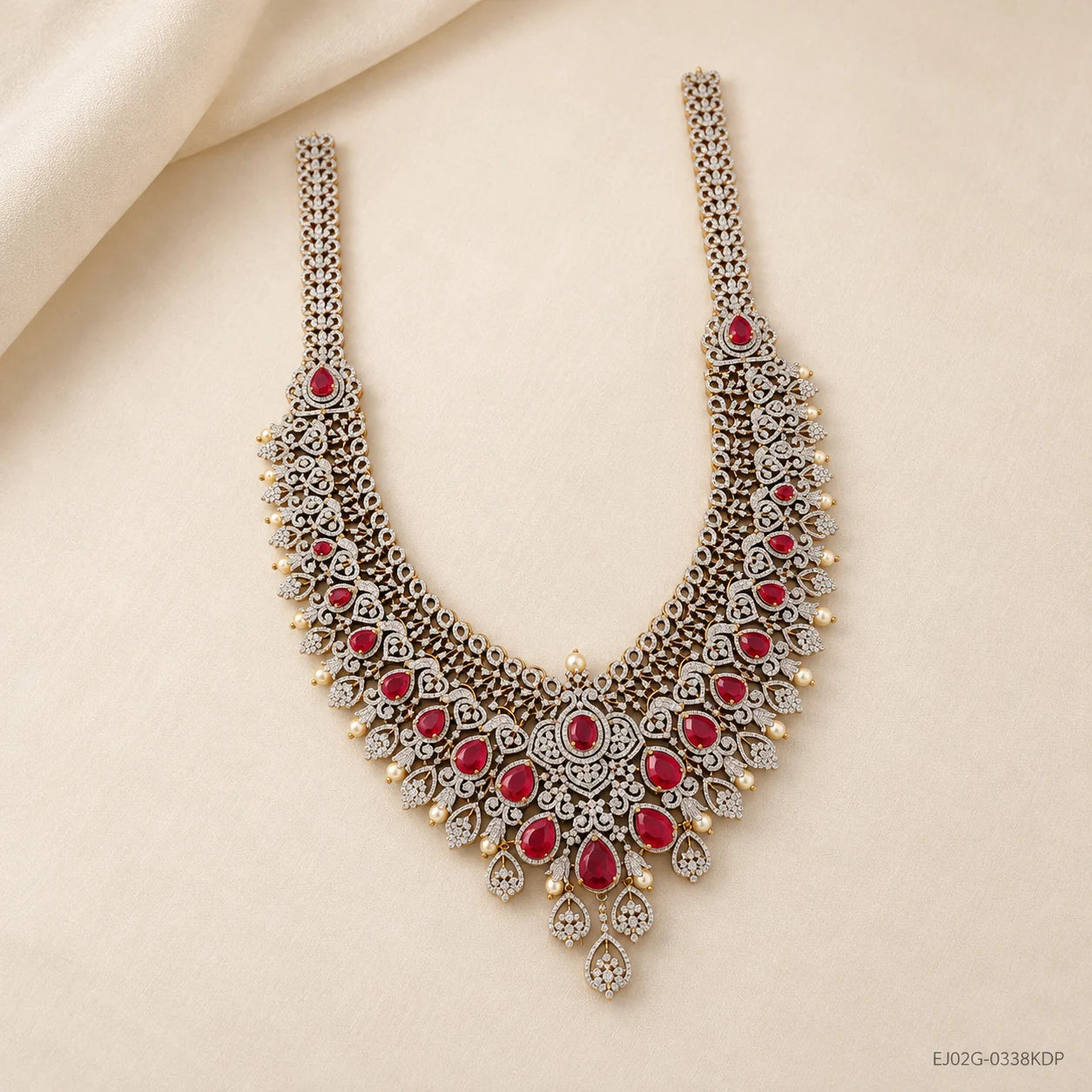 Long necklace on cream backdrop with silk drape, pearl drops dangling along the red stone edges