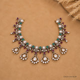Necklace displayed open on a beige surface highlighting the symmetrical drop pendant design