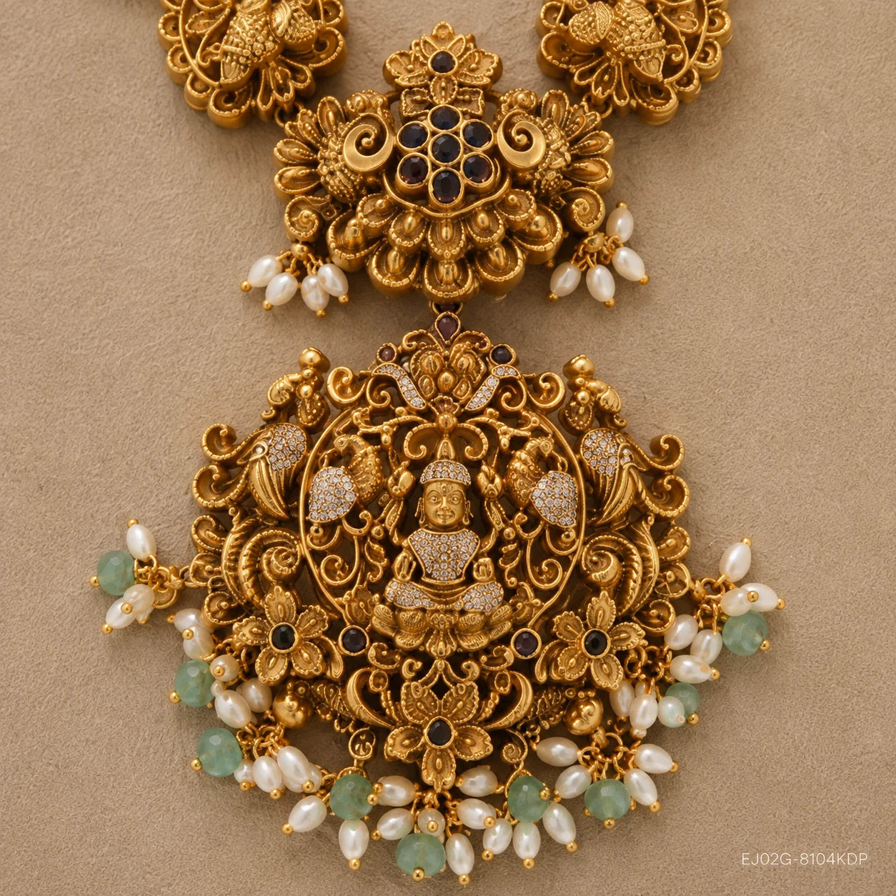 Close-up detail of the pendant showing a carved deity figure, peacock scrollwork and pearl-green bead fringe