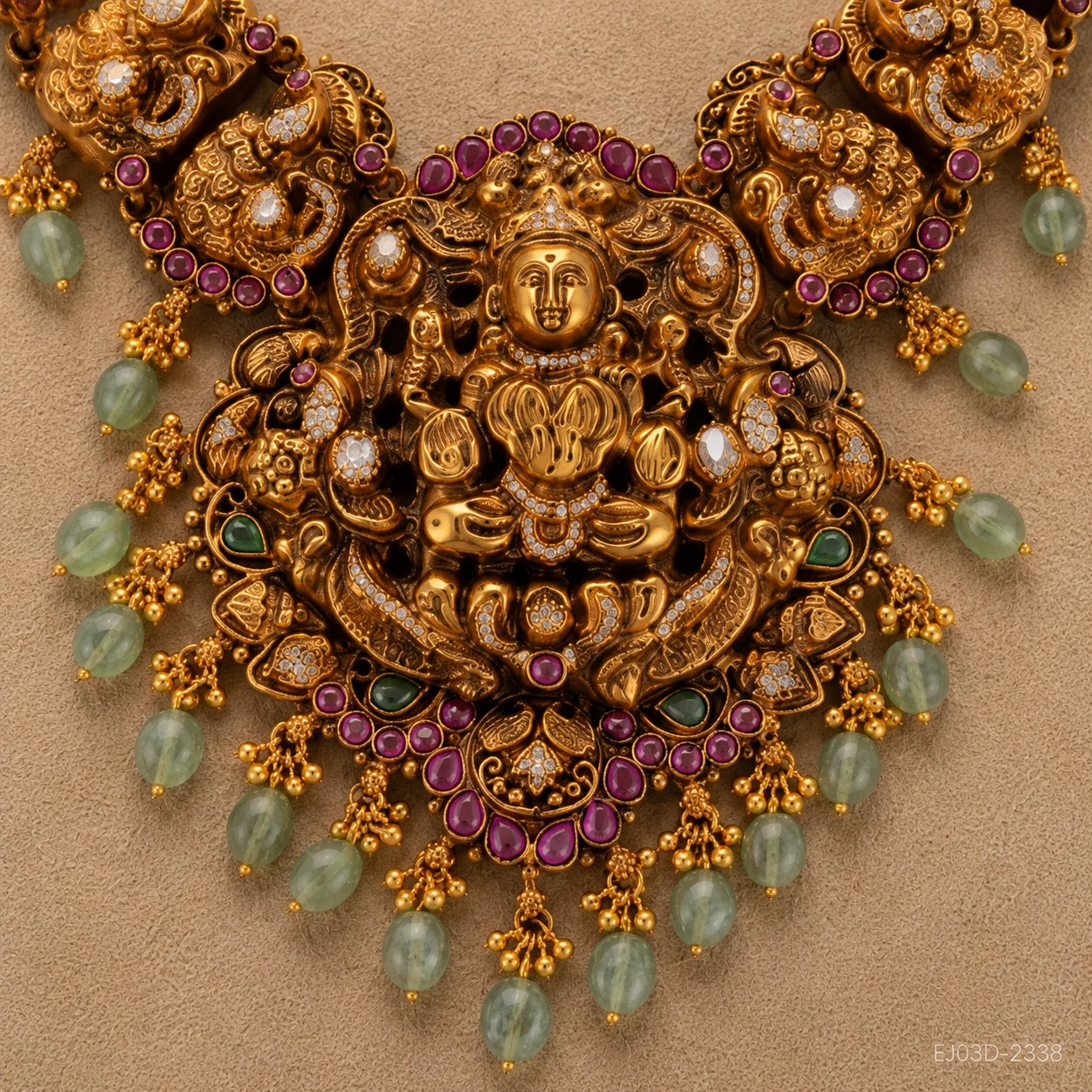 Close-up of the central medallion showing the carved deity figure, pink stones and green bead fringe